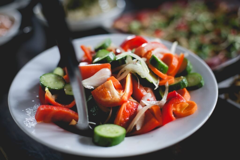 A vibrant fresh vegetable salad with cucumbers and peppers in a white bowl.
